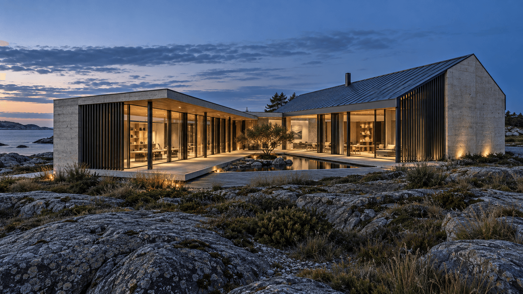 Coastal studio concept with a dark pitched metal roof, concrete walls and warmly lit glazing around a courtyard at dusk